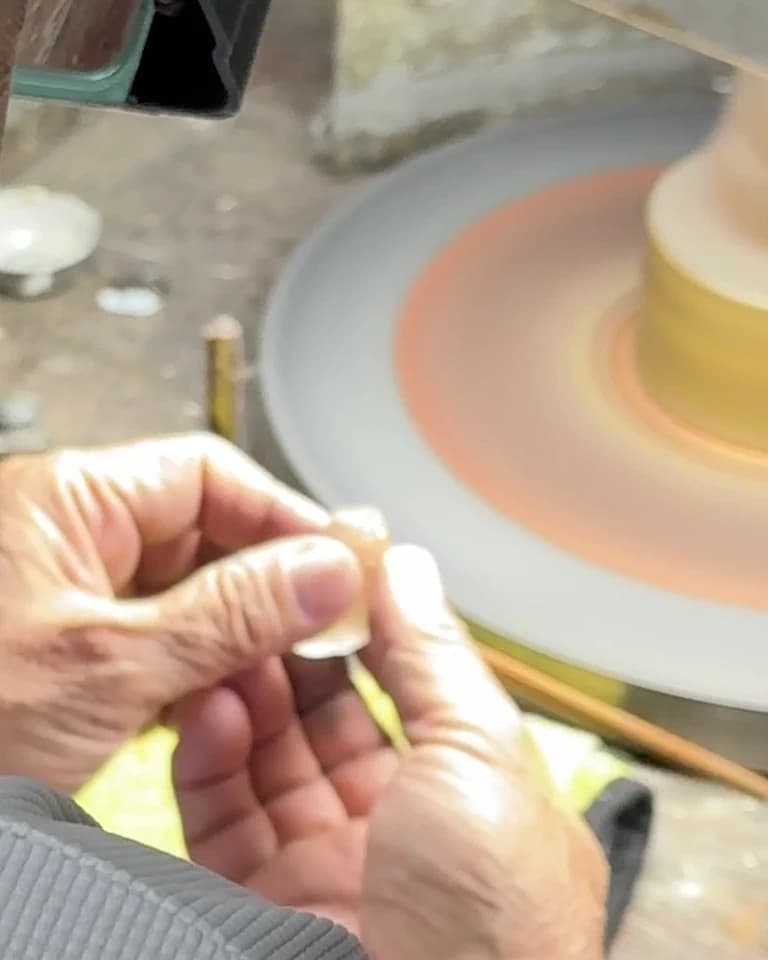 A lapidary turning a Ceylon gemstone against the polishing wheel in the atelier